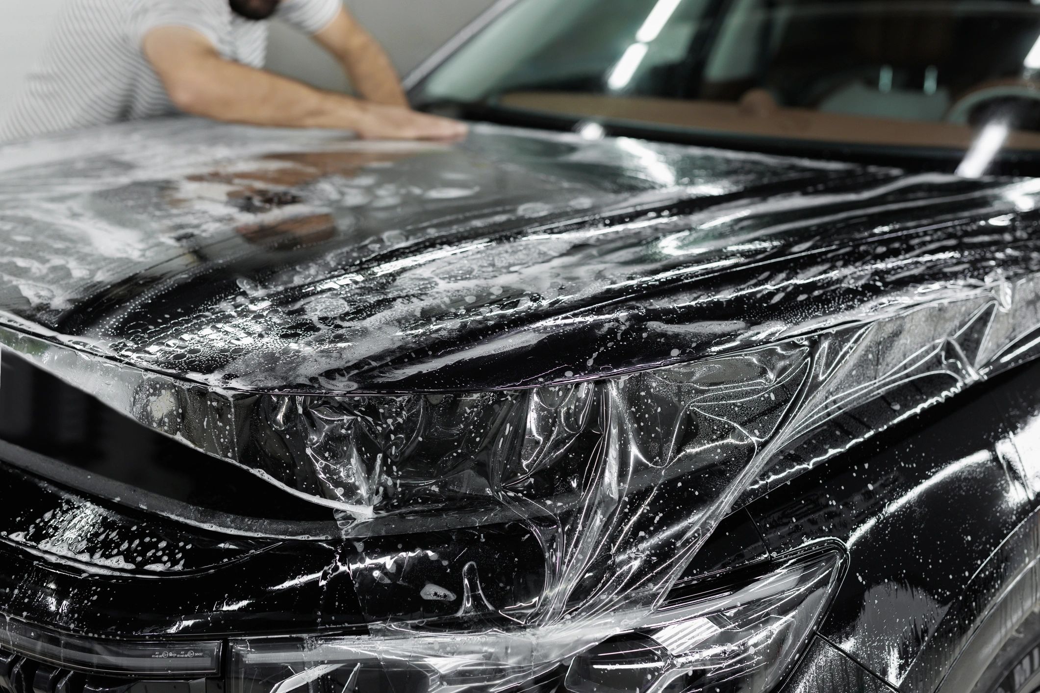 Technician applying paint protection film to a vehicle hood