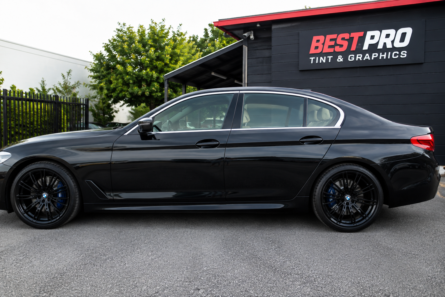 Professionally tinted black luxury sedan parked outside Best Pro Tint and Graphics
